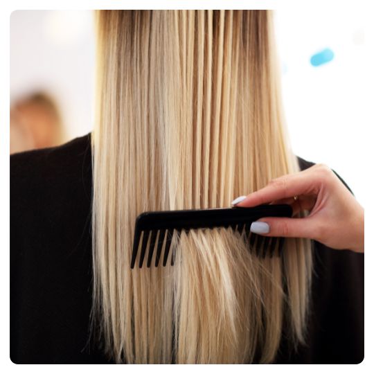 Kvindelig kunde får kørt en kam gennem håret hos frisøren